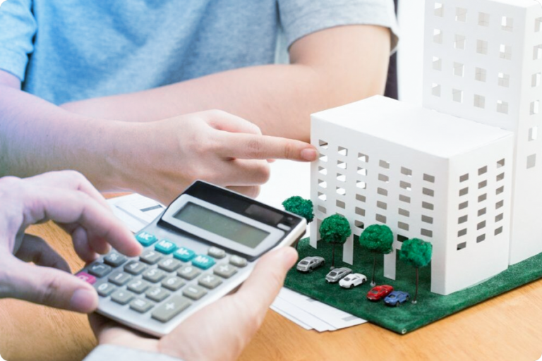 Photo d'une calculette devant la maquette d'un immeuble blanc