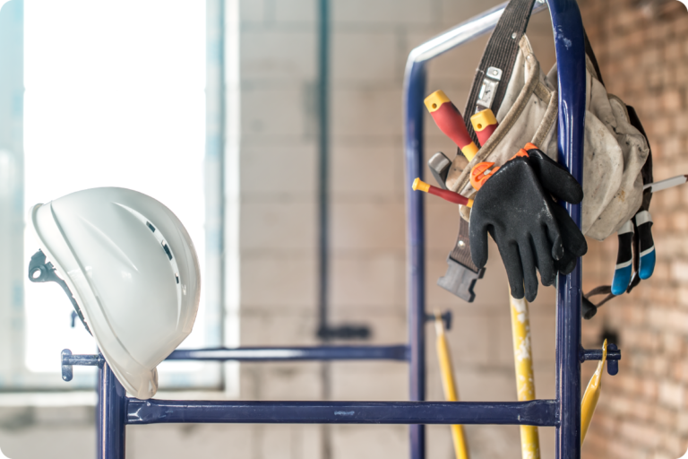 Photo d'un casque de chantier posé à côté d'une paire de gants et d'outils