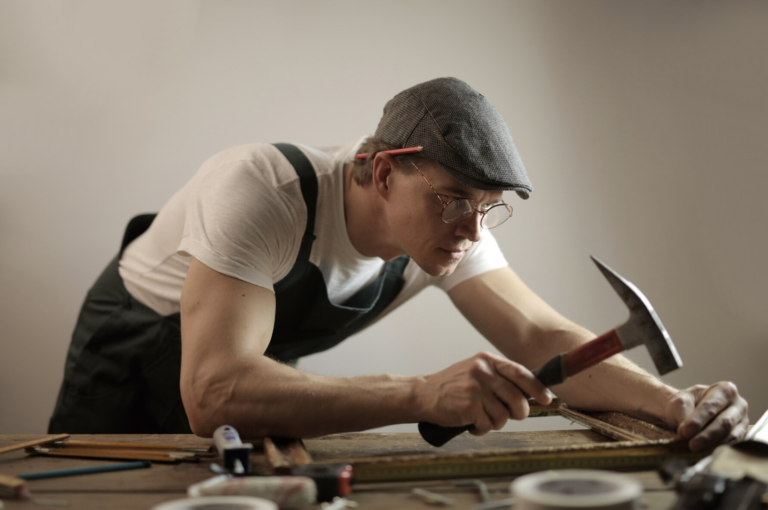 Photo d'un artisan avec une pioche penché sur son plan de travail