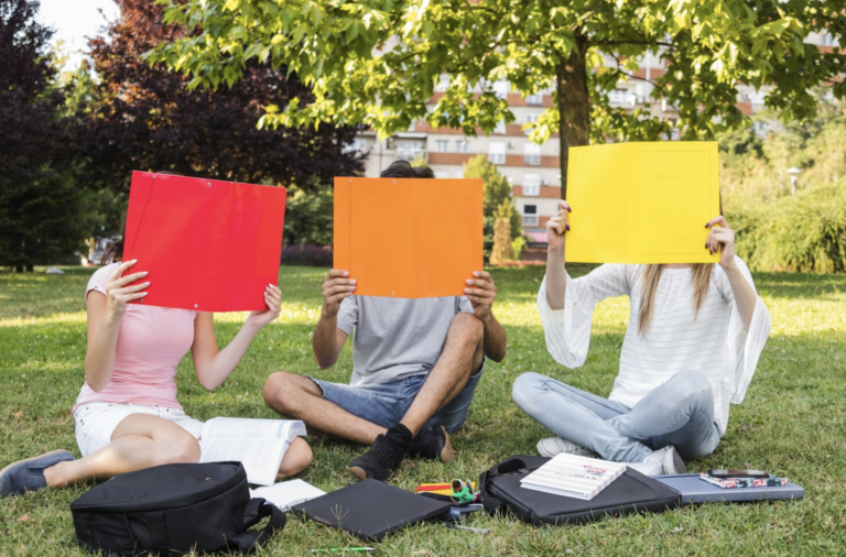 Photo de trois personnes tenant une feuille rouge, une feuille orange et une feuille jaune