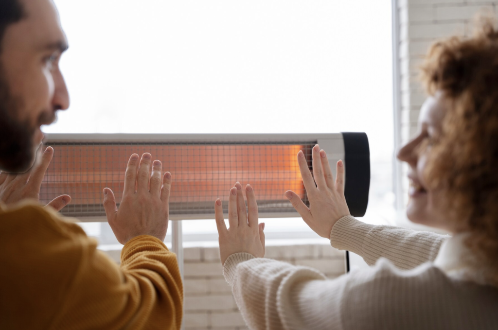Photo d'un couple se réchauffant les mains face à un chauffage
